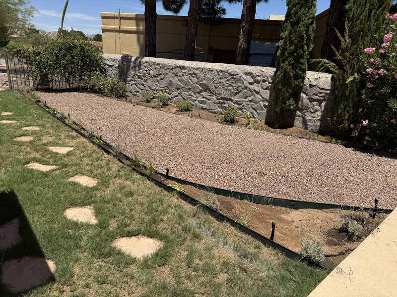 Drip irrigation lines along gravel bed with stone wall border in Las Cruces
