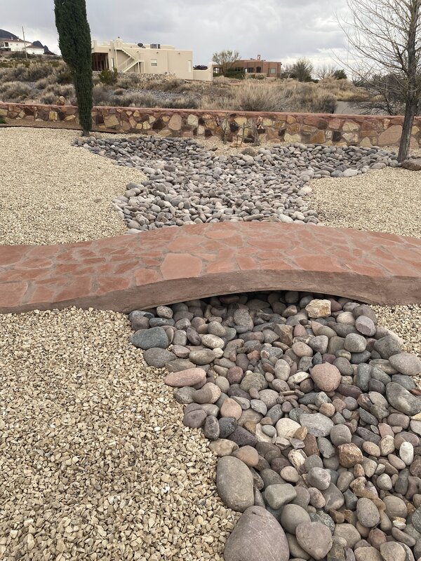 Flagstone bridge over dry creek bed with xeriscape gravel and rock in Las Cruces