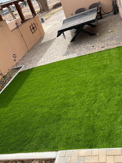 Artificial turf backyard with paver patio and outdoor dining area