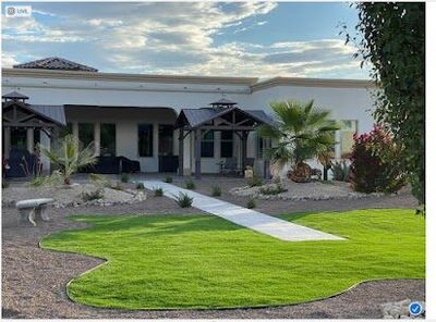 Large estate landscape with shaped artificial turf lawn, covered patios, and desert plantings