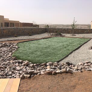Artificial turf with river rock border in a desert backyard setting