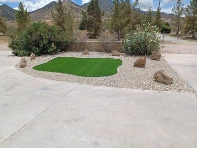 Artificial turf island with accent boulders and gravel in a mountain-view driveway