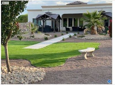 Estate backyard with shaped artificial turf, concrete walkway, dual gazebos, and palm trees