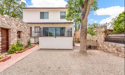 Gravel courtyard with natural stone walls, brick planter, and mature shade tree