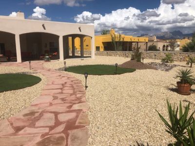Wide view of a southwestern property with flagstone path, artificial turf islands, and Organ Mountain panorama