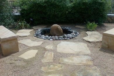 Bubbling stone fountain surrounded by flagstone steppers in a gravel courtyard
