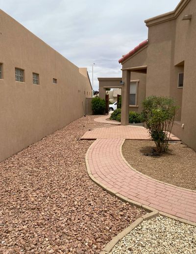 Curving brick paver walkway through gravel beds along a side yard