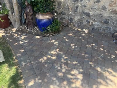 Brick paver patio corner with blue Talavera pottery, statue, and stone wall at a southwestern home
