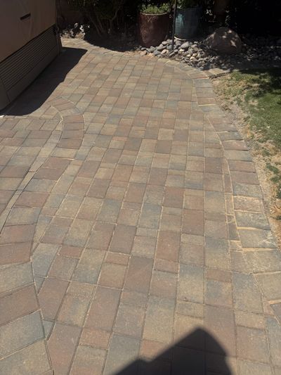 Brick paver walkway with curving border and river rock accent beside a hot tub
