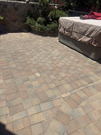 Completed brick paver surface around hot tub with stone retaining wall and plantings
