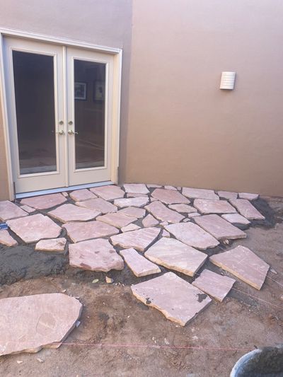 New flagstone being set in mortar near French doors during a Las Cruces patio rebuild