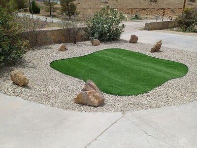 Artificial turf island with accent boulders and white gravel surround