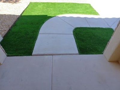 Artificial turf patches flanking a curved concrete walkway at a home entry