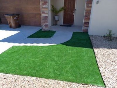 Artificial turf front entry flanking a concrete walkway with brick home facade