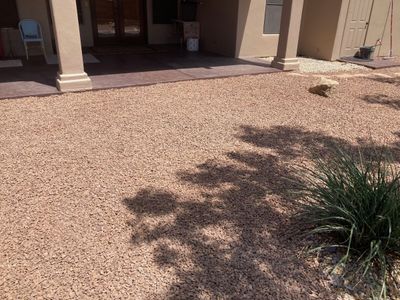 Covered patio overlooking a tan gravel xeriscape yard with ornamental grasses and accent boulders