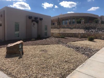 Modern southwestern home with river rock dry creek bed, dual-tone gravel, and stone retaining wall