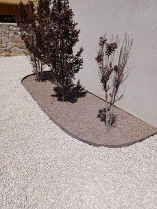 Purple-leaf ornamental trees and shrubs in a shaped mulch bed with white gravel surround
